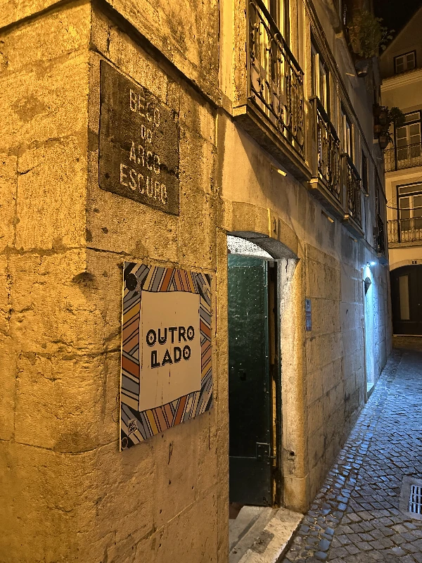 The blue sign above an arch marking the entrance to Outro Lado Craft Beer, tucked down an alley in Baixa, Lisbon