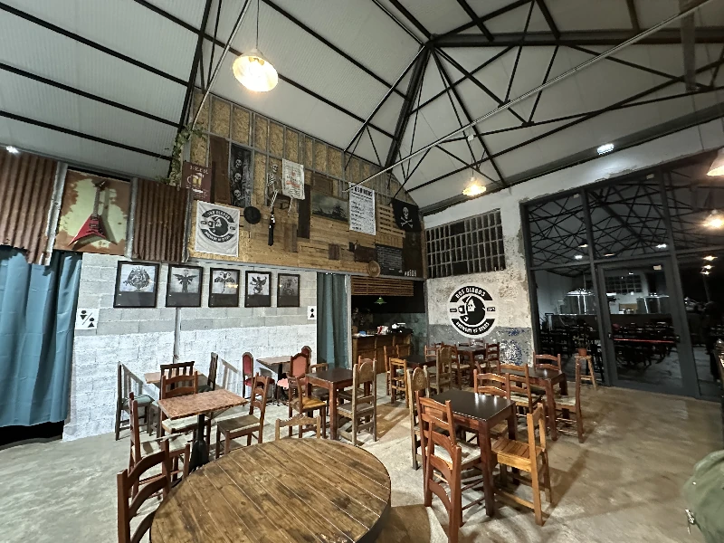 Open brewery interior at Cerveja Dos Diabos Porto with stainless steel fermentation tanks, booths, and bar